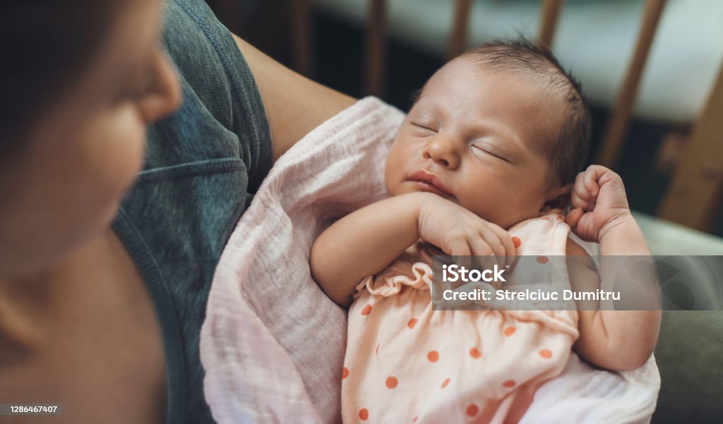 Newborn baby sleeping in safety while mother is holding and smiling at her Baby - Human Age Stock Photo