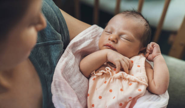 bebê recém-nascido dormindo em segurança enquanto a mãe está segurando e sorrindo para ela - newborn - fotografias e filmes do acervo