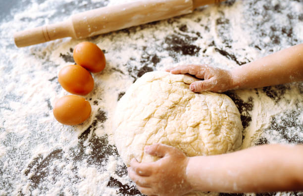 istock Children hands kneading dough for baking.  Kids hands, some flour, wheat dough and rolling pin on the dark table. Cookies for Christmas. 1286467661