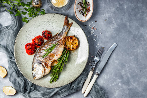 istock Baked dorado fish on a plate with vegetables top view, free space for text 1286468771