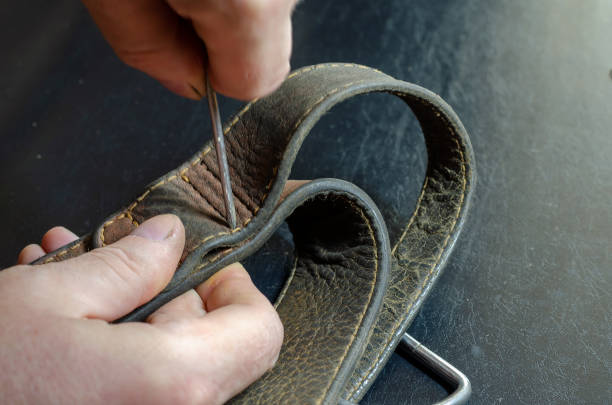istock A man makes holes in a leather collar with an awl. 1286470075