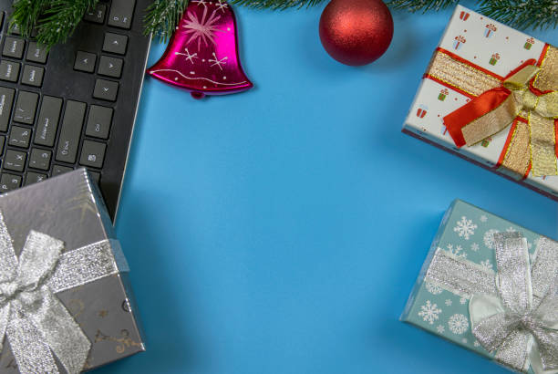 istock Coniferous branches and Christmas balls on the table, computer and a gift box, sparkling Christmas balls. Ordering gifts online from home.. 1286471532