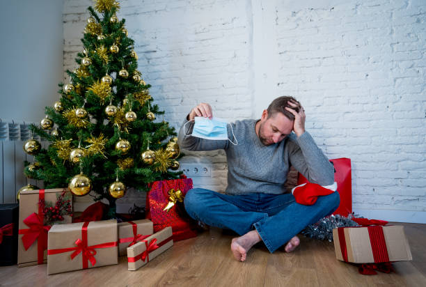 istock Sad man with mask home alone in self isolation at christmas feeling depressed mourning and missing family and friends. COVID-19 Lockdown and quarantine during winter holidays and mental health. 1286472657