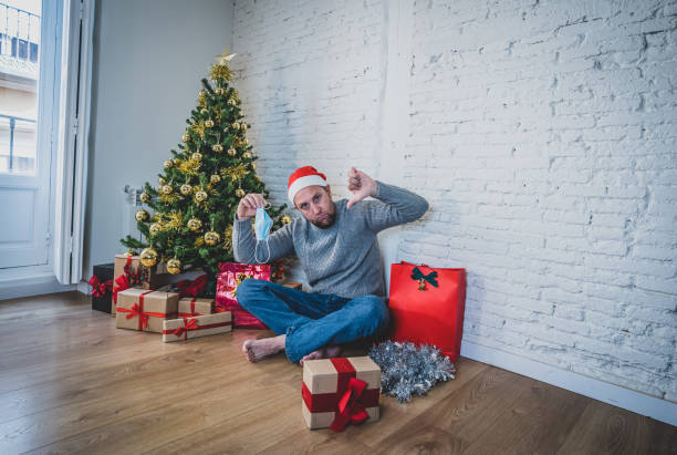 istock Sad man with mask home alone in self isolation at christmas feeling depressed mourning and missing family and friends. COVID-19 Lockdown and quarantine during winter holidays and mental health. 1286472821