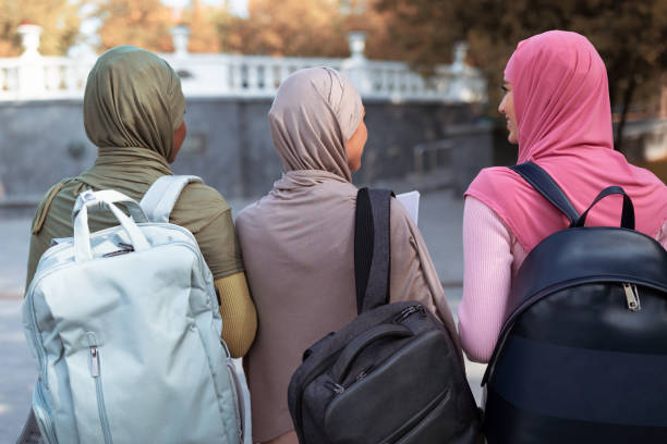 istock Three Muslim Ladies With Backpacks Walking Back To Camera Outdoor 1286472851