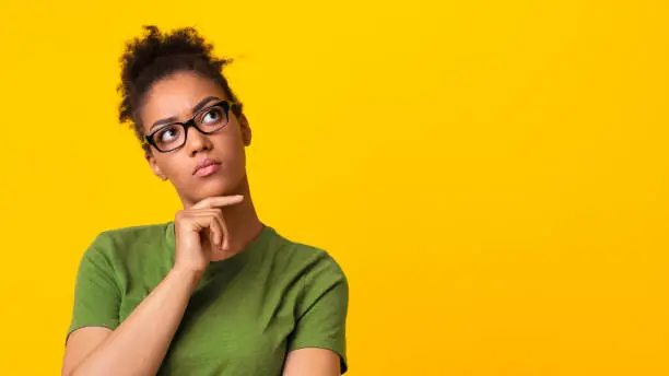 Photo of Black lady in eyeglasses thinking about question, touching chin