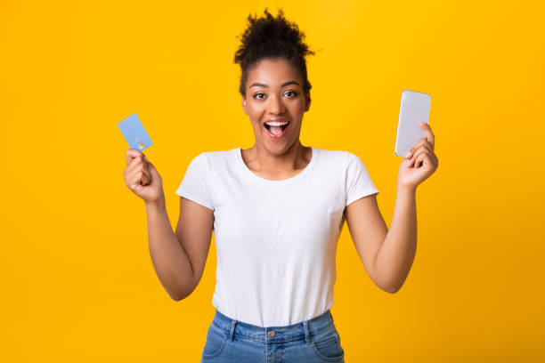 istock Excited black lady holding credit card and cellphone at studio 1286473764
