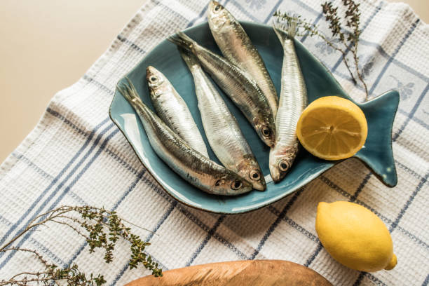 A close-up of one European sardine or Sardina Pilchardus in a larger pile of freshly caught sardines in the Greek fish market.