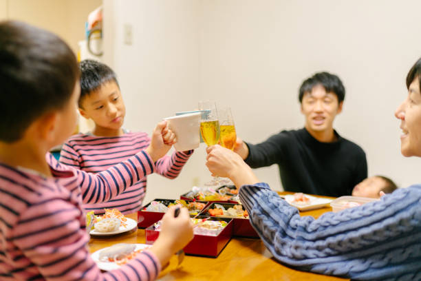 Japanese family enjoying eating together on New Year A Japanese family is enjoying eating osechi ryori, traditional Japanese New Year`s food, during New Year`s day at home. baby new years eve new years day new year stock pictures, royalty-free photos & images