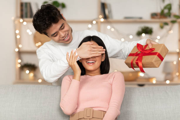 istock Husband Giving Xmas Present To Wife Making Surprise At Home 1286477862