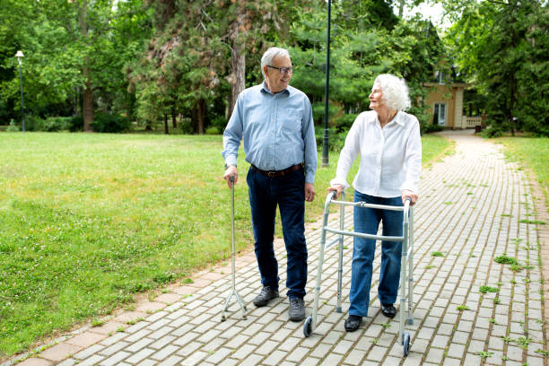 istock Senior man using a walking cane accompanied by a senior lady strolling with folding walker 1286479043