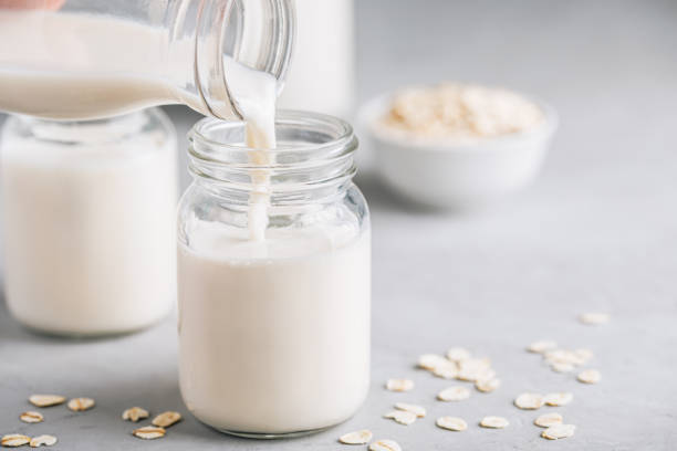 oat milk in glass. vegan non dairy oat milk on gray stone background - milk milk bottle drinking straw cookie imagens e fotografias de stock