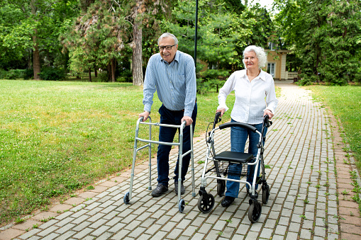 Senior citizens walking through the park with walking aid, elderly concept