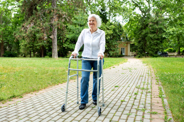 Elder woman holding to a walker as she strolls through the park