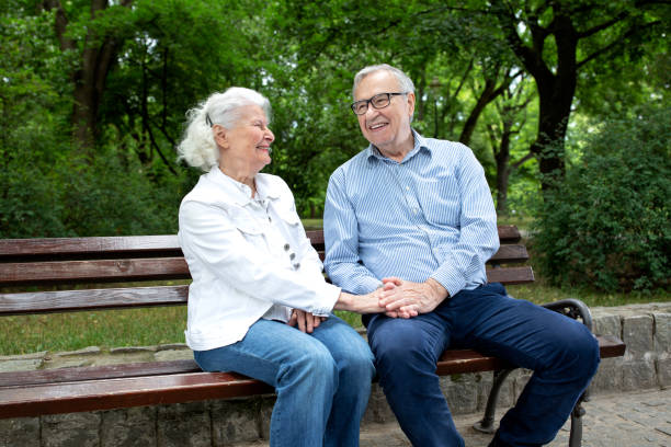 istock Senior couple holding hands while sitting in the park 1286479527