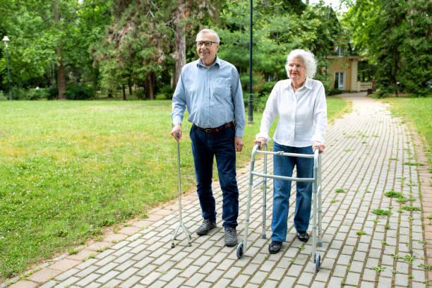 istock Senior man using a walking cane accompanied by a senior lady strolling with folding walker 1286479707