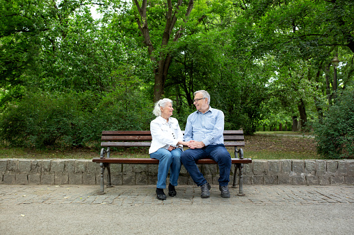 Never ending love between a senior couple caught by the eye of camera on the bench in the park