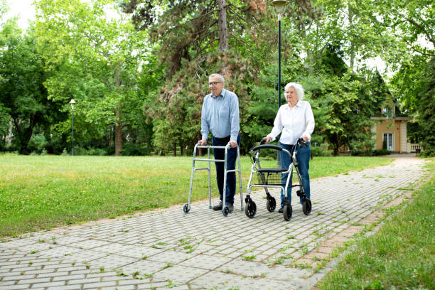 istock Elderly couple in the park strolling with walkers 1286480841