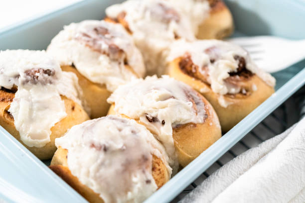istock Freshly baked cinnamon rolls with white icing in a blue baking pan. 1286482176