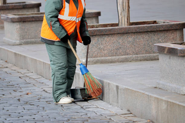 Street cleaning, female municipal worker in uniform sweeping the sidewalk with a broom Janitor in winter city, concept of unskilled labor street sweeper stock pictures, royalty-free photos & images