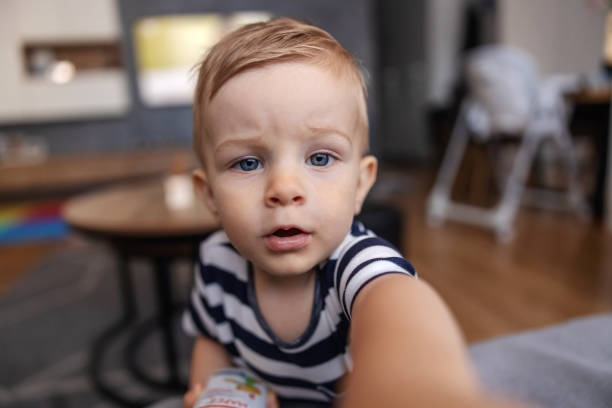 istock Adorable blond youngster curiously looking and reaching for camera. 1286484386