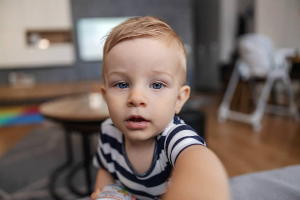 istock Adorable little blond boy reaching for camera and looking at it. 1286484460