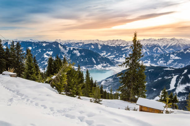 冬のゼラー湖でツェルアムゼー。オーストリアのアルプス山脈にあるスキーリゾートの雪の斜面、シュミッテンホーエ山からの眺め。カプルン近くの雪と夕日の空を持つ見事な風景 - lake mountain north tirol austria ストックフォトと画像