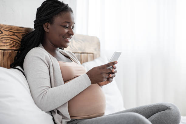 istock Joyful Black Pregnant Lady Spending Time With Smartphone At Home, Browsing Internet 1286485895