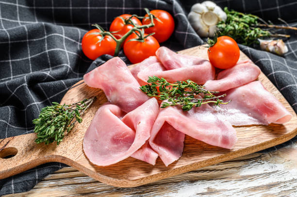 istock Sliced ham. Fresh prosciutto. Pork ham sliced. White wooden background. Top view 1286485910