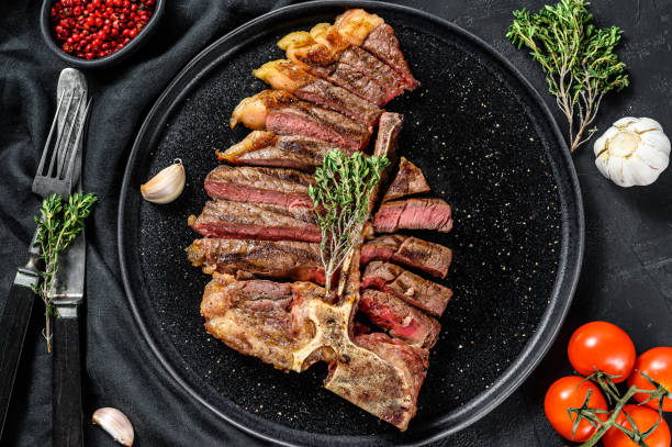 istock Sliced Grilled Florentine steak. T bone meat beef. Black background. Top view 1286485971
