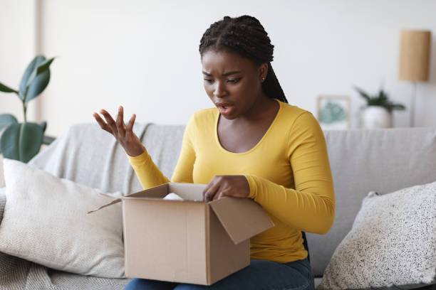 istock Wrong Parcel. Shocked frustrated black woman unpacking box, suffering from shipping mistake 1286486113