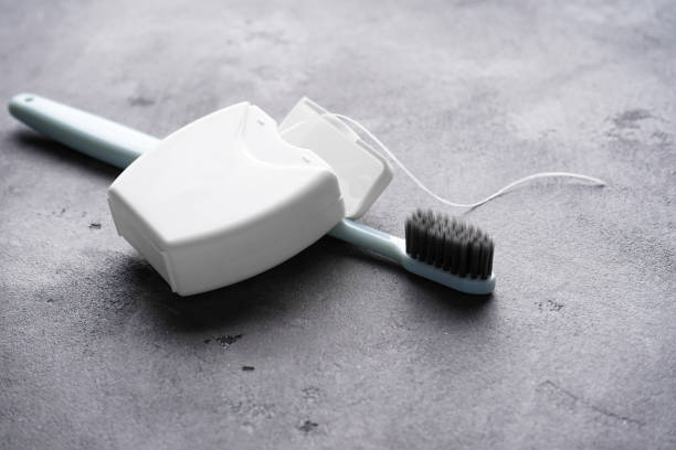 Toothbrush with dental floss on a gray background, close-up. stock photo