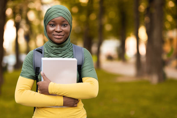 educação para mulheres muçulmanas. senhora estudante negra em hijab posando ao ar livre - african ethnicity standing college student curly hair - fotografias e filmes do acervo