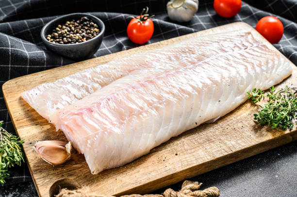 istock Fresh Raw Cod loin fillet with thyme.  Black background. Top view 1286490553