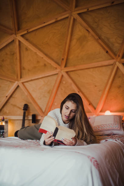 istock Young woman reading a book on a bed 1286490590