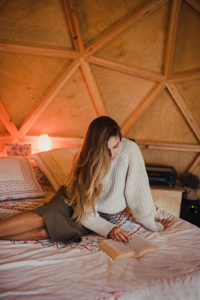 istock Young woman reading a book on a bed 1286490730