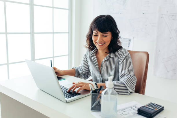 istock Cheerful woman sitting at her office desk and working 1286491220