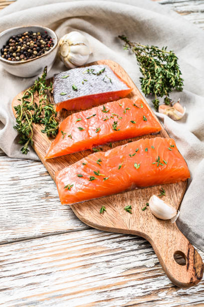 istock Salted salmon fillet with thyme. White wooden background. Top view 1286492476
