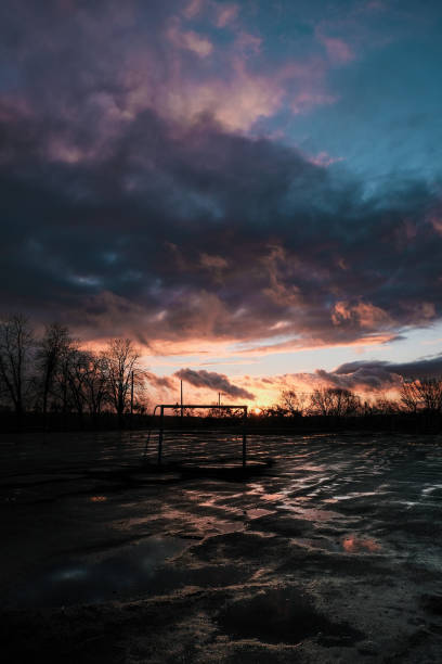 Sunset clouds after the rain over field with puddles Sunset cloudy landscape after the rain over abandoned soccer field with puddles gloriole stock pictures, royalty-free photos & images