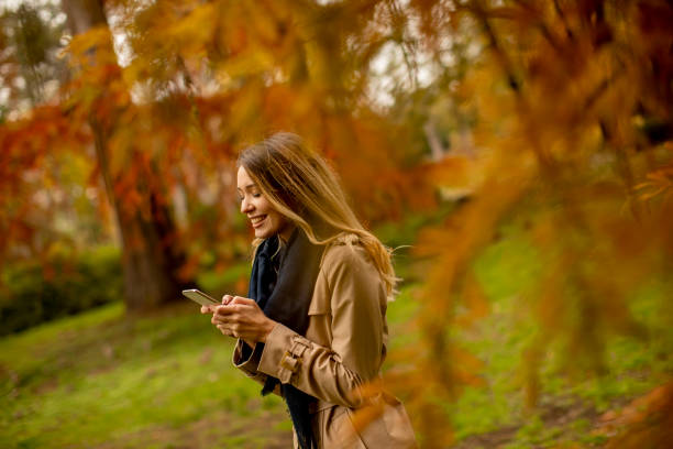 istock Young woman using mobile phone in the autumn park 1286498175