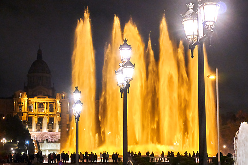 Barcelona, Spain - December 19, 2019: Crowd of people marvel at the magical fountain at night.