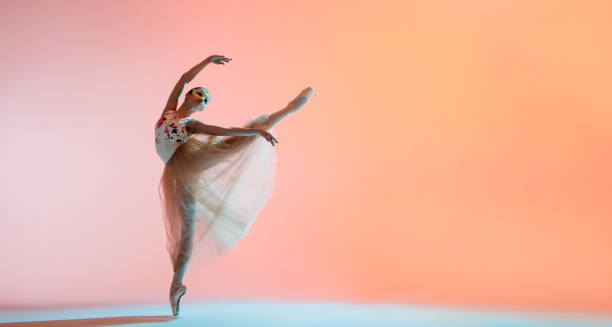 istock Ballerina in a light dress is dancing on colored background with backlight 1286498609