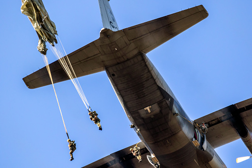 Military paratroopers parachute jumping out of a Air Force C-130 Hercules transport plane during the Operation Market Garden memorial. The Netherlands - September 21, 2019
