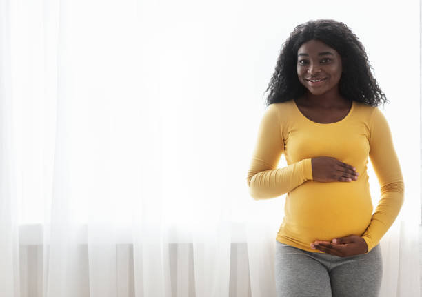 istock Smiling black lady carrying baby, hugging her big tummy 1286501940