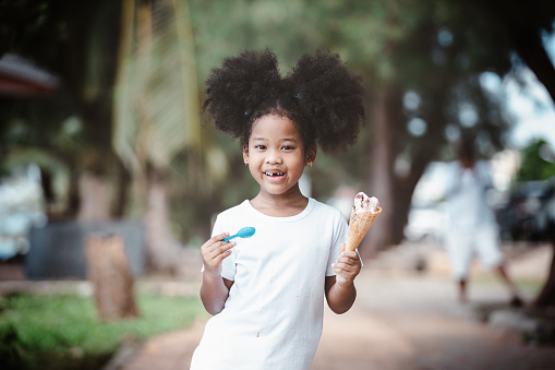 African American Little girl eating ice cream cone in the outdoor park