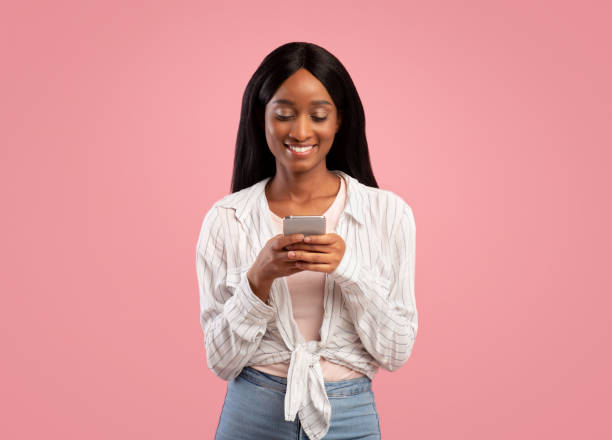 istock Online life concept. Attractive black woman using smartphone on pink studio background 1286502178