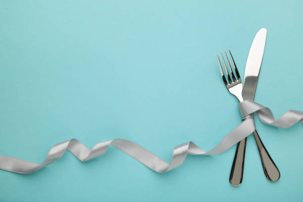 istock Christmas table place setting on blue background. Knife and fork with silver ribbon on blue 1286502600
