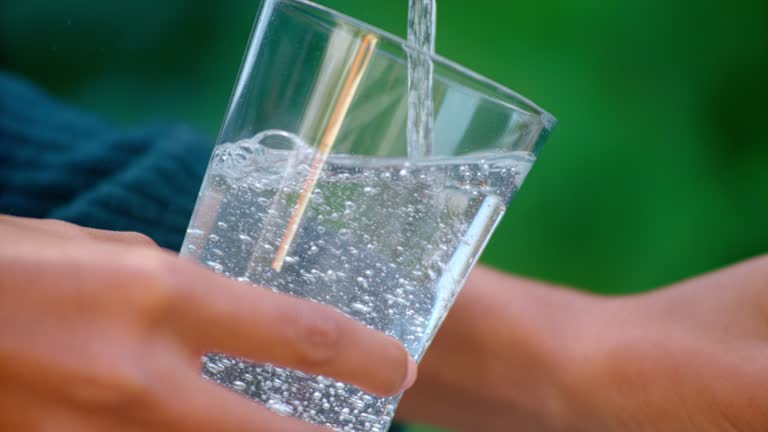 SLO MO TD Hands of woman filling a glass with water from the garden faucet