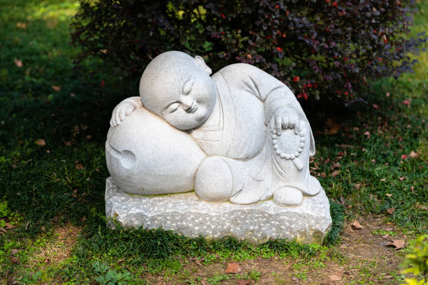 une petite statue d’un petit moine dormant à un jardin dans le temple bouddhiste historique de jinshan - zhenjiang photos et images de collection