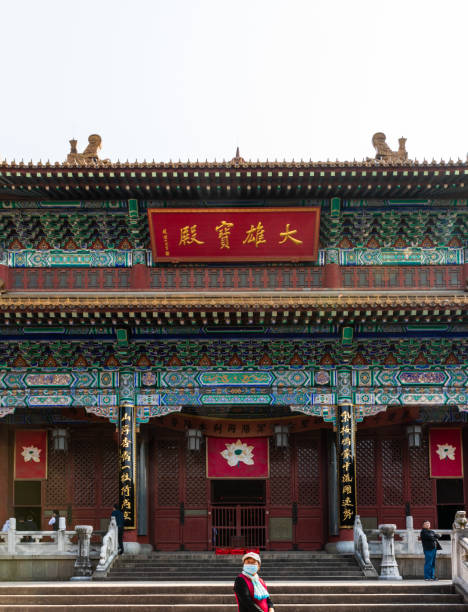 femme avec le masque devant mahavira ou hall principal dans le temple bouddhiste historique de jinshan - zhenjiang photos et images de collection